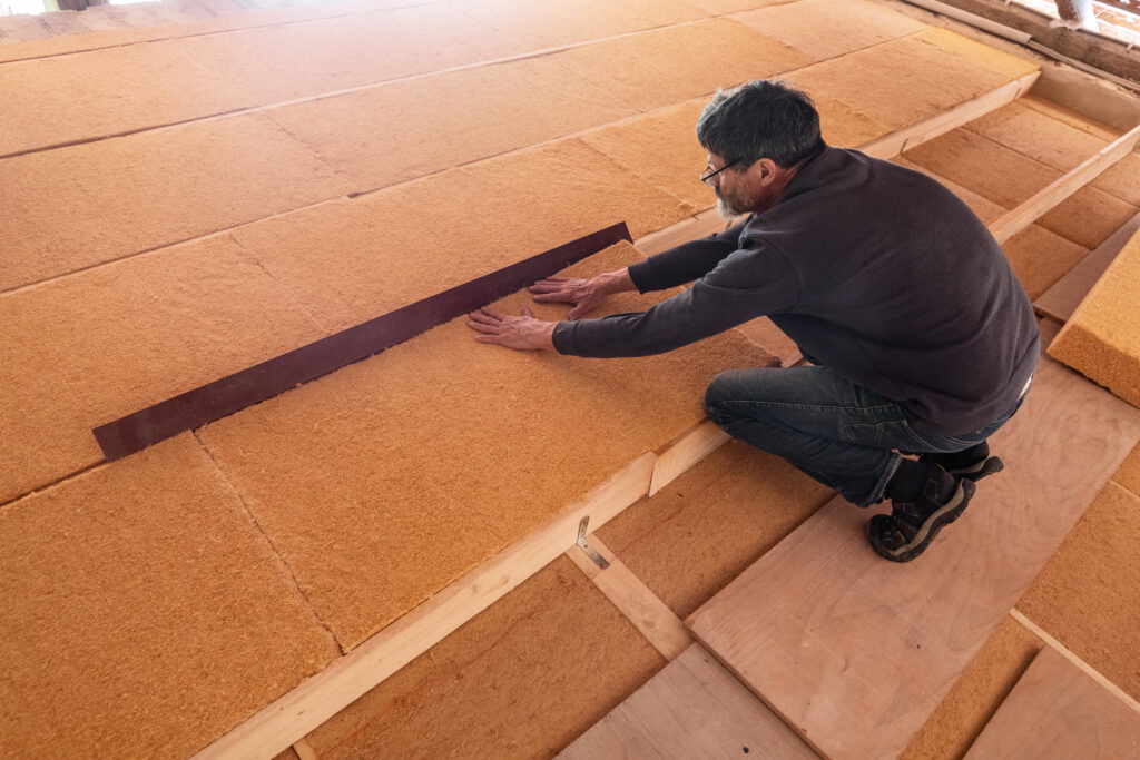 Zimmermann verlegt Holzweichfaserplatten im Dachboden